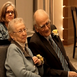 Senior couple seated together during ceremony.